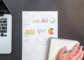 Overhead view of a business desk with charts and a laptop, ideal for data analysis concepts.